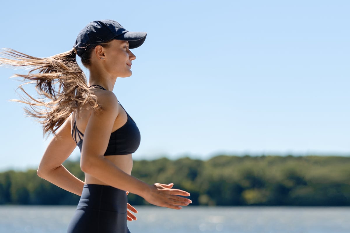 Runner in monochrome running kit beside a calm lake